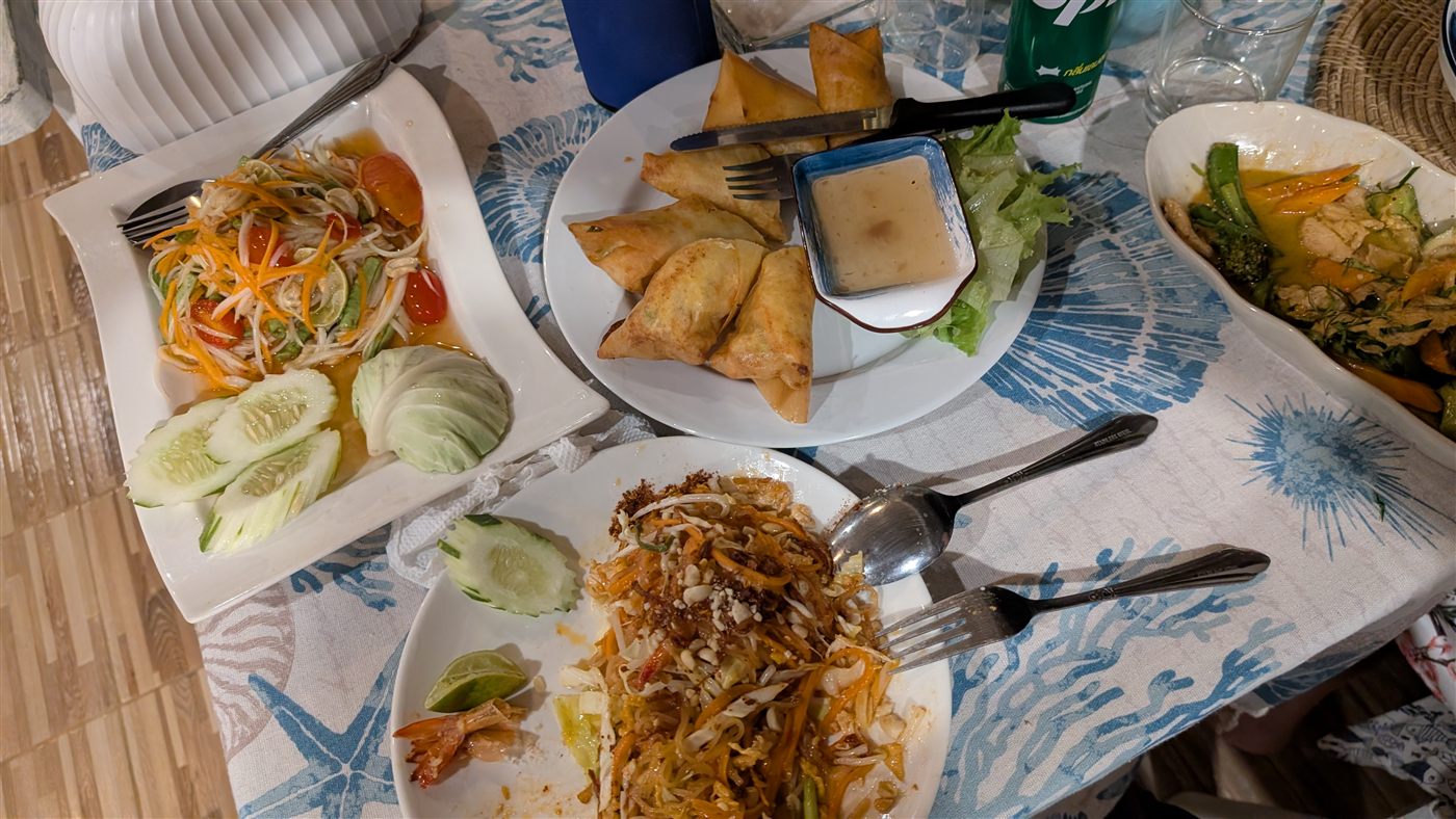 Thailändisches Abendessen mit Som Tam, Samosas und Pad Thai auf dem Tisch
